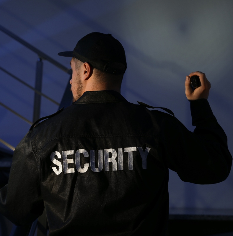 male security guard with flashlight going up stairs in darkness